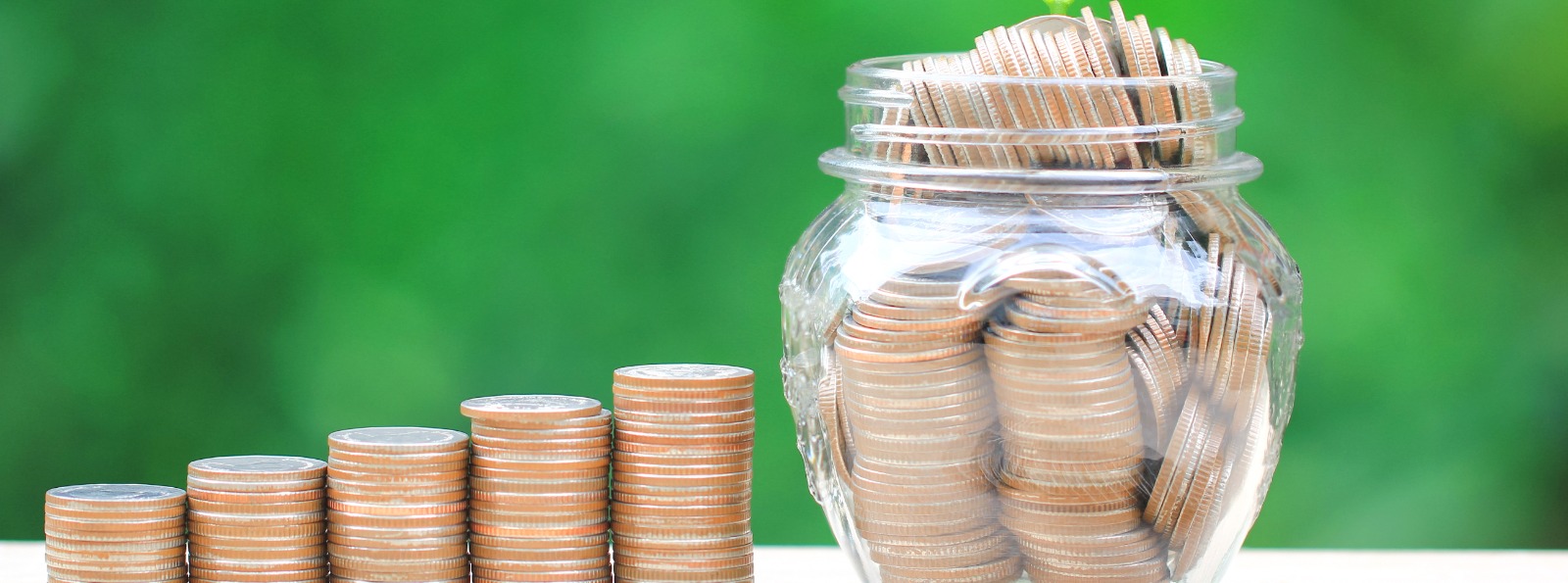 a glass jar filled with coins next to a set of stacked coins